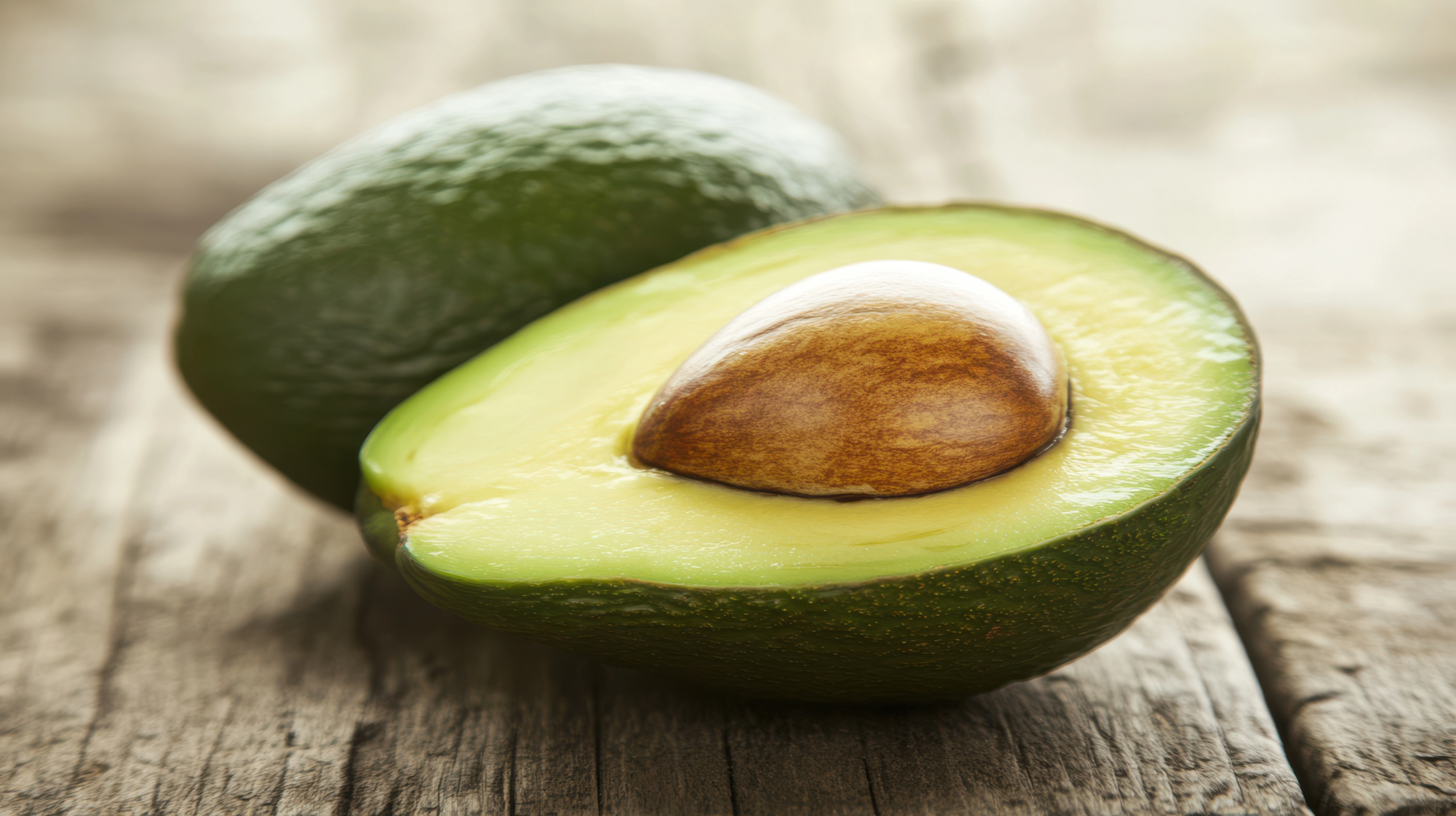 avocado halved with pit sitting on wooden table